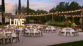 Outdoor wedding reception at Bel Vino Winery featuring illuminated LOVE sign, string lights, and elegant round tables.
