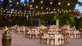 Elegant outdoor reception courtyard at Bel Vino Winery with rustic tables, floral centerpieces, and vineyard backdrop.