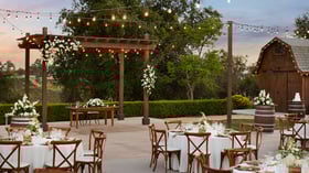 Romantic courtyard wedding reception with round tables, string lights, and vineyard views at Bel Vino Winery.