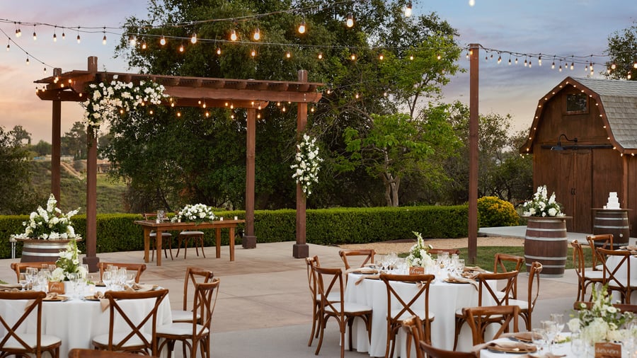 Romantic courtyard wedding reception with round tables, string lights, and vineyard views at Bel Vino Winery.