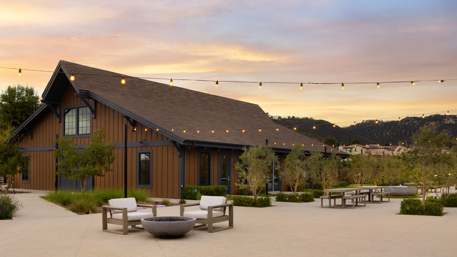 Outdoor wedding patio with firepit seating and string lights glowing against a mountain sunset backdrop at Canopy Grove.