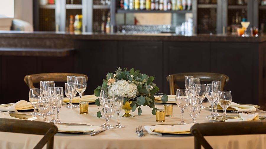 Elegant wedding table setting at Carlsbad Windmill Loft with gold chargers, glassware, and floral centerpiece.