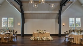 Sweetheart table at Carlsbad Windmill Loft with floral arrangements and warm wood flooring.