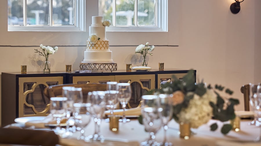 Elegant wedding cake display at Carlsbad Windmill Loft with gold-accented decor and fresh florals.