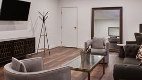 Groom’s room in Carlsbad Windmill Garden Suite with seating, TV, and modern accents.