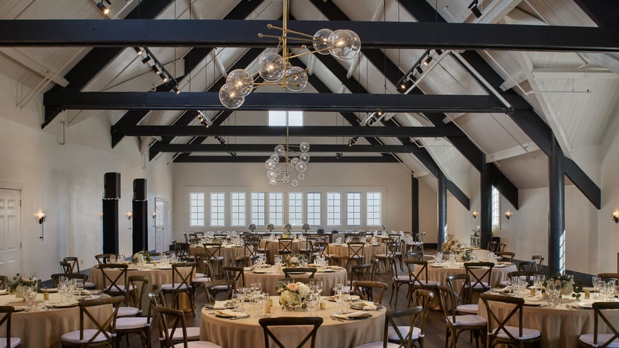 Carlsbad Windmill Loft reception with round tables, neutral linens, and floral centerpieces.