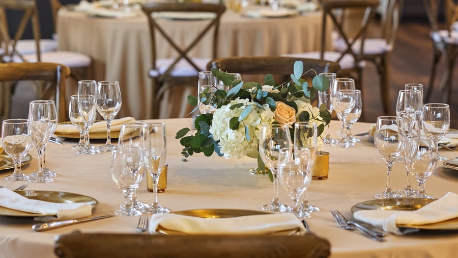 Floral centerpiece with white and peach roses at Carlsbad Windmill Loft wedding reception.