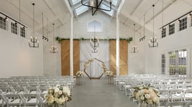 Bright Carlsbad Windmill chapel wedding ceremony with floral hexagon arch and white chairs.