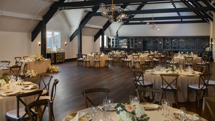 Stylish Carlsbad Windmill Loft reception hall with wooden cross-back chairs and gold accents