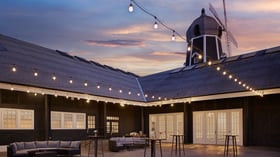 Carlsbad Windmill Palm Courtyard outdoor cocktail hour with string lights and sunset backdrop.