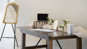 Wedding welcome table at Colby Falls in Arizona with guestbook, floral décor, gold mirror welcome sign, and gift card box.