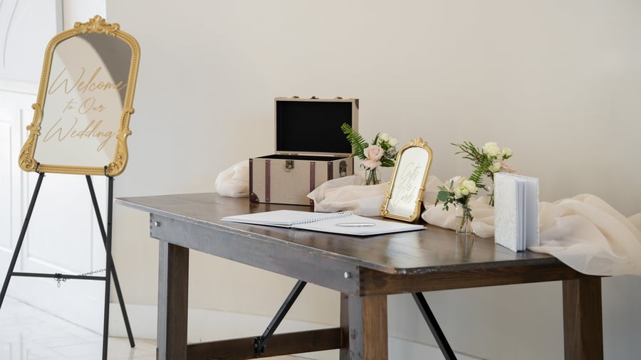 Wedding welcome table at Colby Falls in Arizona with guestbook, floral décor, gold mirror welcome sign, and gift card box.