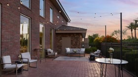 Cocktail hour patio at Colby Falls Arizona with brick exterior, string lights, modern lounge seating, and sunset views.