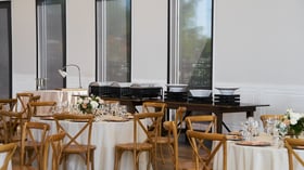 Buffet station setup inside Colby Falls Grand Hall Arizona, with banquet tables, chafing dishes, and rustic wood reception chairs.