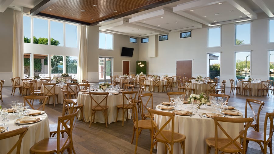 Grand Hall at Colby Falls in Arizona decorated for a wedding reception with round tables, rustic chairs, and natural light through tall windows.