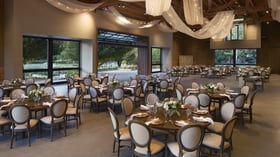 Spectacular reception hall at Galway Downs featuring dramatic ceiling draping with twinkling lights, elegant round tables, neutral linens, and floor-to-ceiling windows showcasing garden views in Temecula
