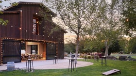 Charming rustic wedding barn at Galway Downs decorated with warm string lights and cocktail tables, perfect for outdoor evening receptions in Temecula wine country
