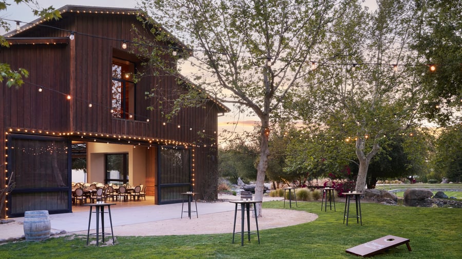 Charming rustic wedding barn at Galway Downs decorated with warm string lights and cocktail tables, perfect for outdoor evening receptions in Temecula wine country