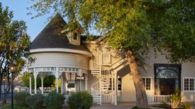 Exterior of Lindsay Grove Grand Hall in Mesa, AZ featuring a Victorian-style turret, spiral staircase, and garden landscaping.
