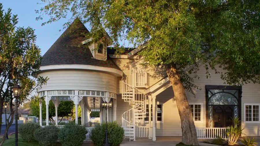 Exterior of Lindsay Grove Grand Hall in Mesa, AZ featuring a Victorian-style turret, spiral staircase, and garden landscaping.