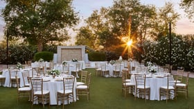 Sunset wedding reception at Lindsay Grove’s brick patio in Mesa, AZ with round tables, gold chiavari chairs, white linens, and romantic string lights.