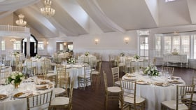 Elegant indoor wedding reception at Lindsay Grove Grand Hall in Mesa, AZ featuring chandeliers, draped ceilings, and white table settings.
