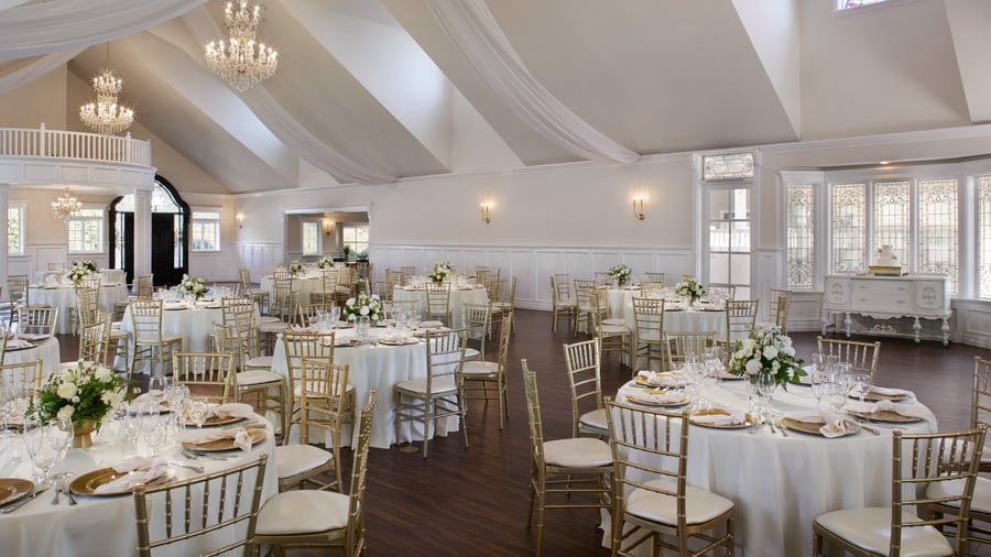 Elegant indoor wedding reception at Lindsay Grove Grand Hall in Mesa, AZ featuring chandeliers, draped ceilings, and white table settings.