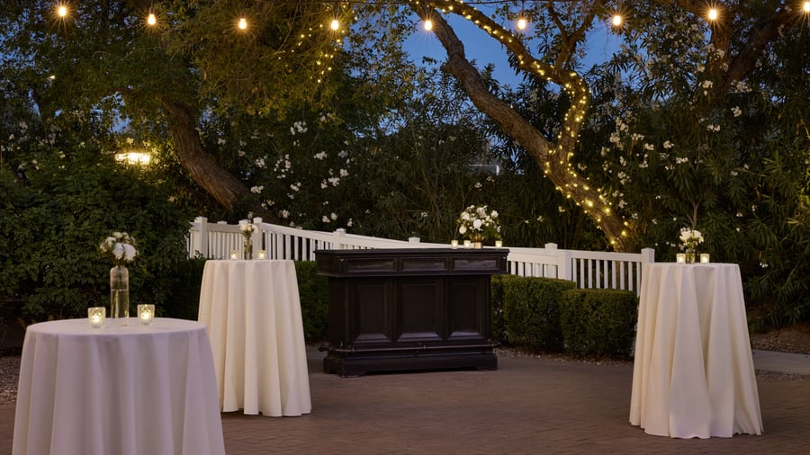 Outdoor cocktail hour at Lindsay Grove in Mesa, AZ with tall cocktail tables, glowing string lights, and floral centerpieces.