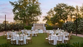 Charming outdoor reception at Lindsay Grove in Mesa, AZ with round tables, white linens, floral centerpieces, and string lights overhead.