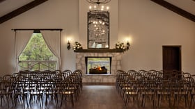 Indoor wedding ceremony setup at Scenic Springs Grand Ballroom in Helotes, TX, with rows of chairs facing a fireplace altar.