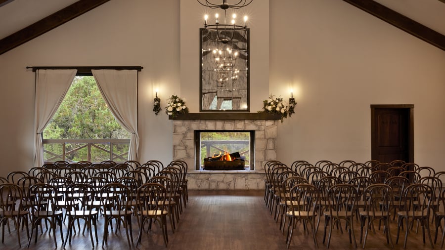 Indoor wedding ceremony setup at Scenic Springs Grand Ballroom in Helotes, TX, with rows of chairs facing a fireplace altar.