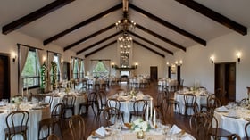 Scenic Springs Grand Ballroom wedding reception in Helotes, TX, with round tables, floral centerpieces, and rustic wood beam ceiling.