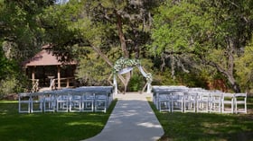 Scenic Springs outdoor wedding ceremony site in Helotes, Texas, with a floral arch centerpiece and natural forest setting.