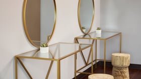 Stylish vanity setup at The Pines with two gold-framed mirrors, glass tables, and natural wood stools, perfect for bridal party preparations.