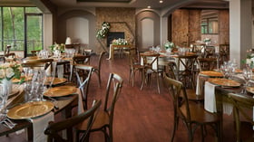 Elegant indoor reception at The Pines featuring a stone fireplace, wood tables with gold décor, and romantic floral arrangements.