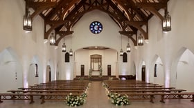 Elegant wedding ceremony setup in The Sanctuary Cathedral, Long Beach, with rose window and floral aisle arrangements.