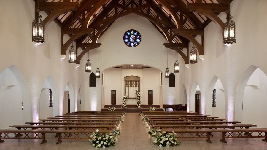 Elegant wedding ceremony setup in The Sanctuary Cathedral, Long Beach, with rose window and floral aisle arrangements.