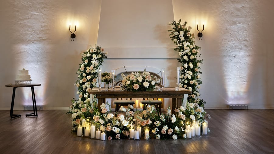 Sweetheart table in The Sanctuary’s Grand Hall, Long Beach, surrounded by lush florals and candles for a romantic wedding reception.