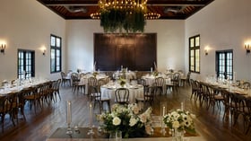 Grand Hall at The Sanctuary in Long Beach set for a wedding reception with round and long tables under a greenery chandelier.