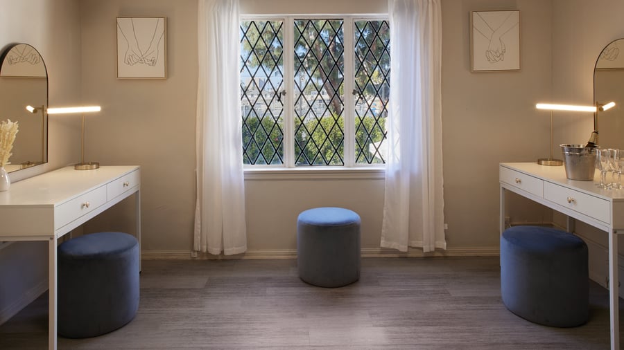 Bright wedding suite vanity area at The Sanctuary in Long Beach with matching mirrors, seating, and diamond-pane windows