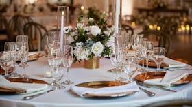 Elegant wedding reception centerpiece at The Sanctuary in Long Beach with white roses, greenery, and candlelight
