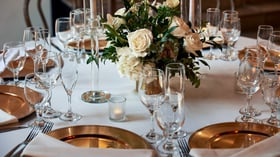 Close-up of wedding reception place setting in The Sanctuary Grand Hall, Long Beach, with gold flatware and glassware.