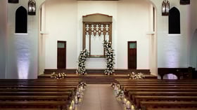 Close-up of the wedding altar at The Sanctuary Cathedral in Long Beach, adorned with white floral arches and candlelit aisle.