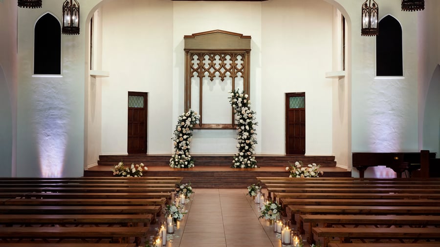 Close-up of the wedding altar at The Sanctuary Cathedral in Long Beach, adorned with white floral arches and candlelit aisle.