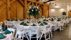 Elegant barn reception setup with white florals and forest green napkins at Alexander Homestead wedding venue