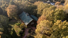 Rustic barn wedding venue with green metal roof nestled among fall foliage at Alexander Homestead in Charlotte, perfect for autu