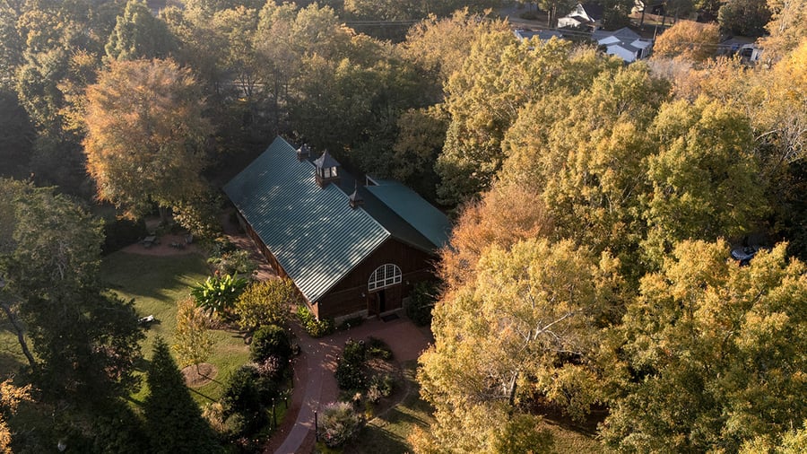 Rustic barn wedding venue with green metal roof nestled among fall foliage at Alexander Homestead in Charlotte, perfect for autu