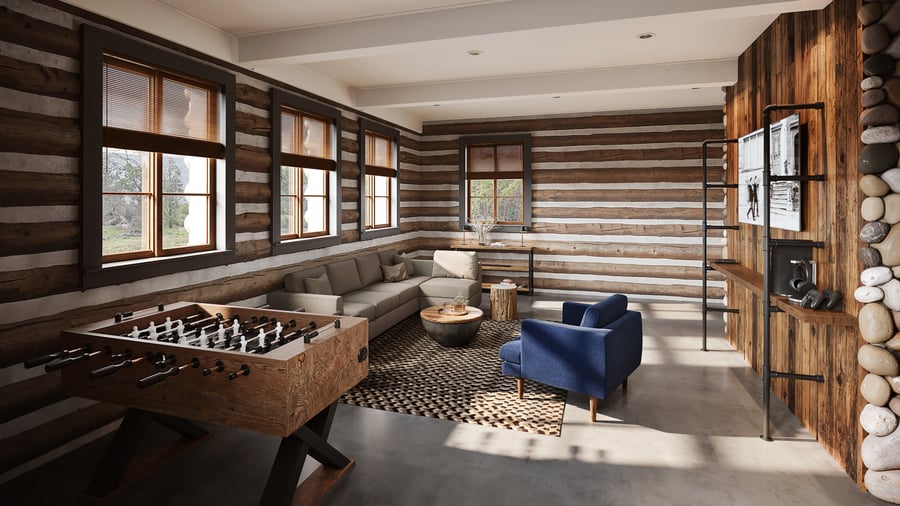 Contemporary lounge area at Casa del Rio Fresno featuring rustic log walls, large windows, foosball table, sectional gray sofa, blue accent chair, wooden coffee tables, geometric area rug, and river stone accents for casual gathering spaces.
