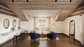 Bright preparation suite at Casa del Rio Fresno featuring wooden beam ceiling, white walls, built-in vanity with three oval mirrors, cream loveseat, navy blue accent chairs, wooden coffee table, and full-length mirror in a rustic-modern design.