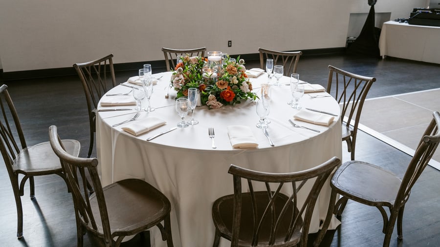 Classic indoor reception with dark hardwood floors, ivory linens, and vibrant centerpieces at Fillmore Chapel by Wedgewood Events